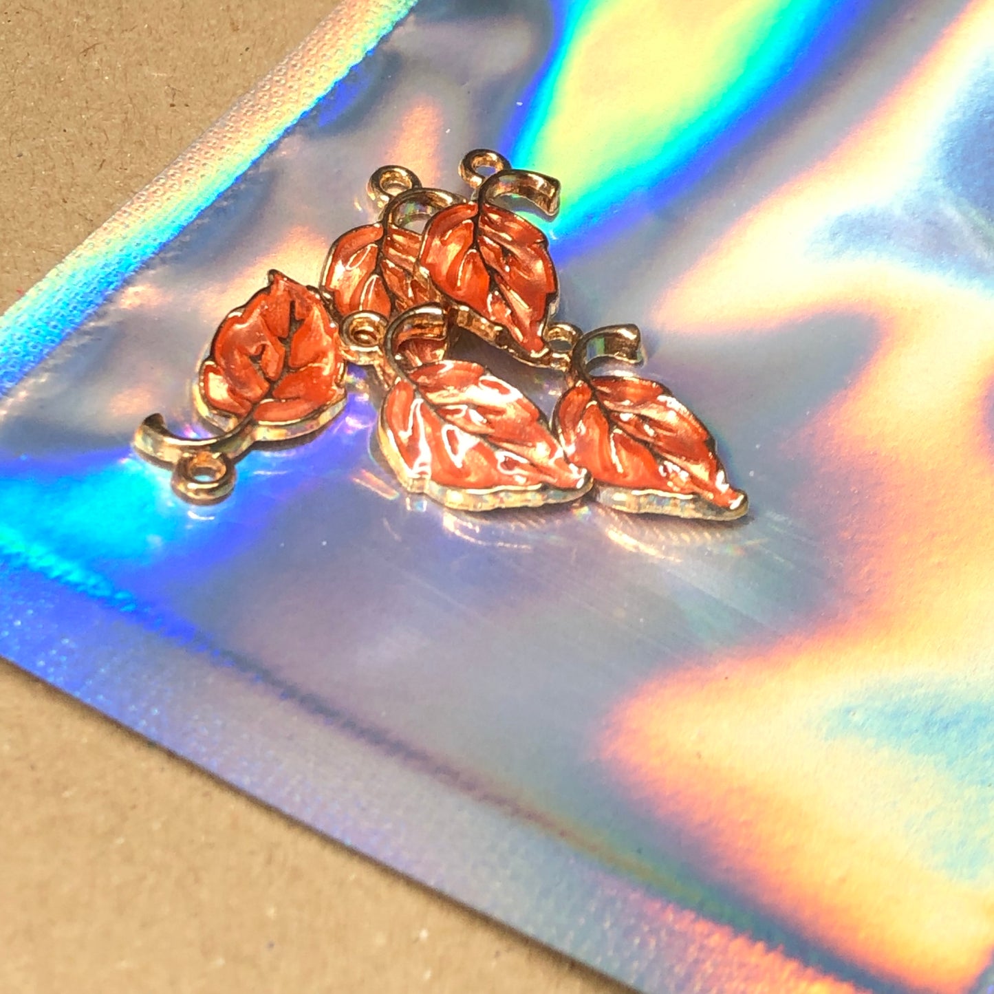 Five peach enamel leaf charms