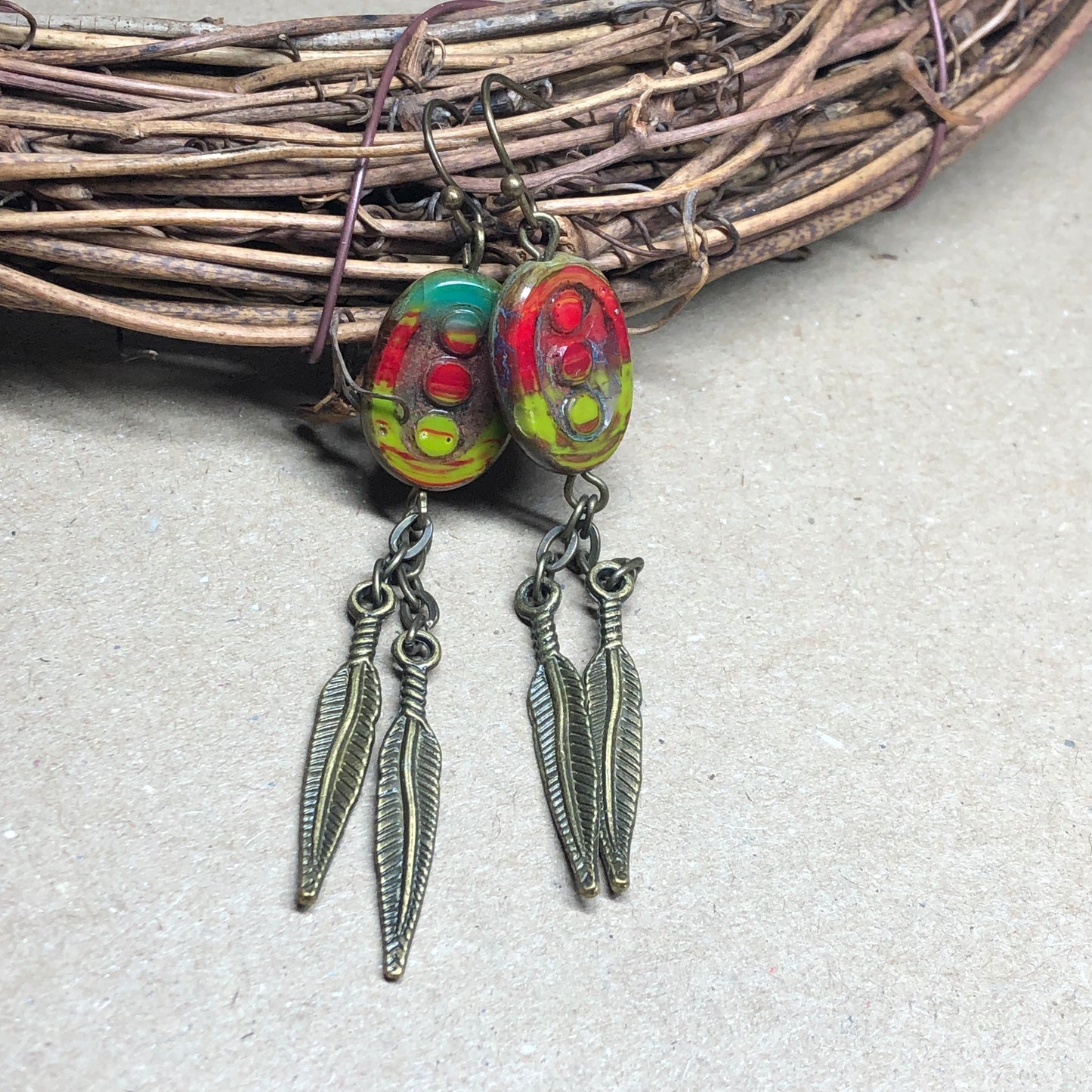 Feather charm earrings with red and green glass beads